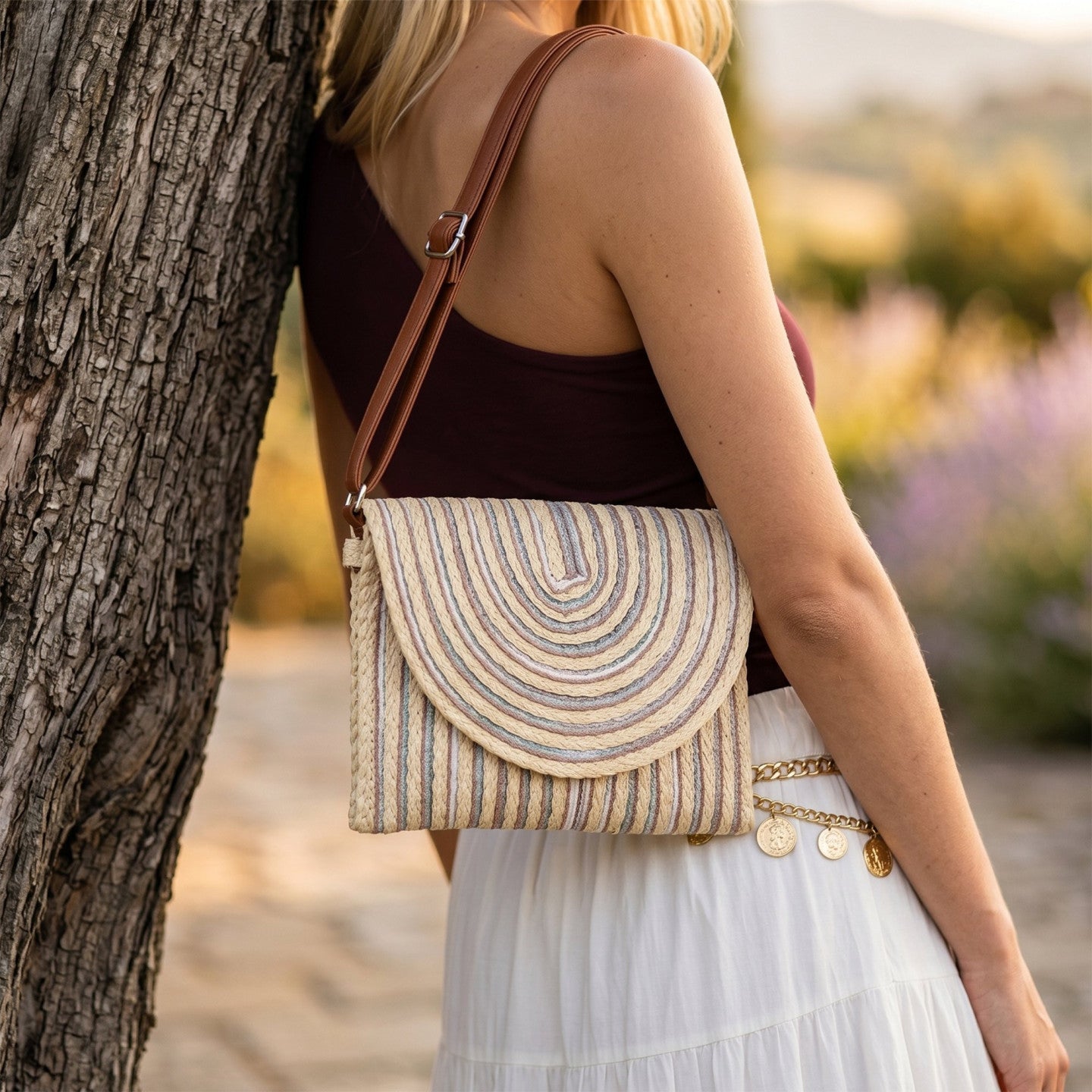 Bolso bandolera de paja con líneas coloridas visto de frente sobre un fondo neutro.